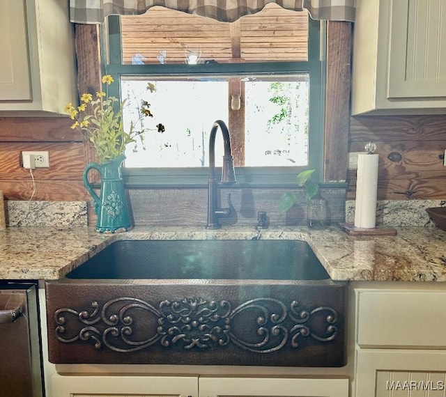 interior details featuring light stone counters and a sink