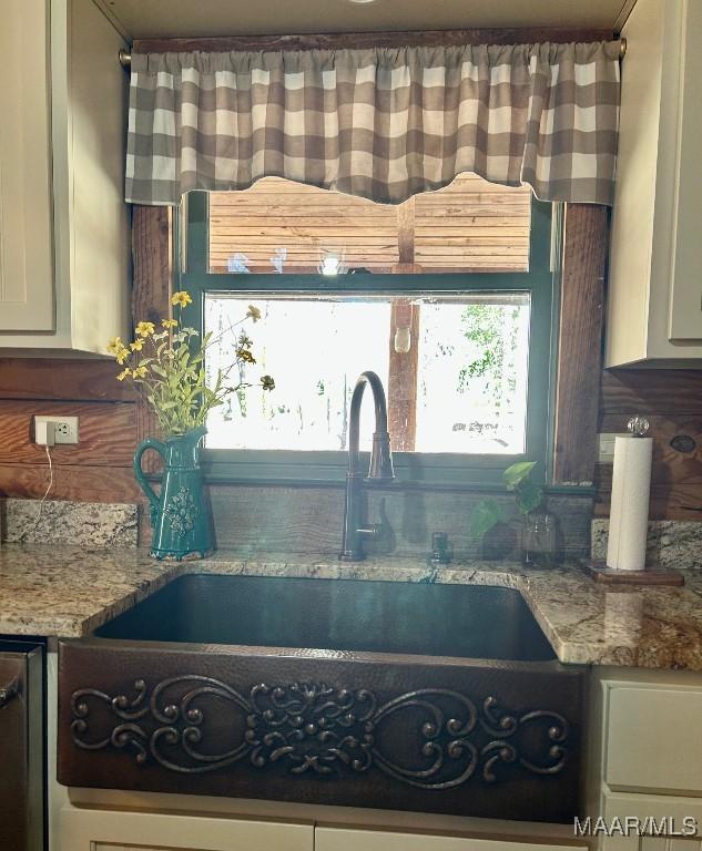 interior space with a sink, white cabinets, and light stone countertops