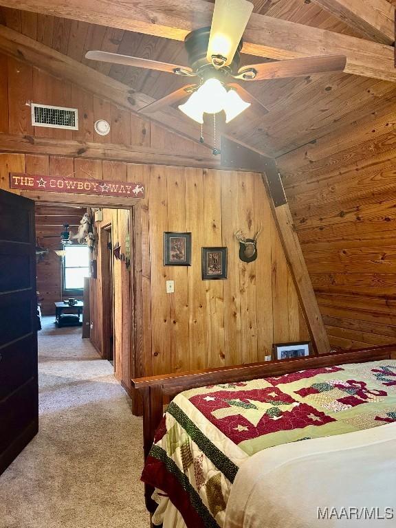 carpeted bedroom with wooden walls, visible vents, a ceiling fan, wood ceiling, and vaulted ceiling