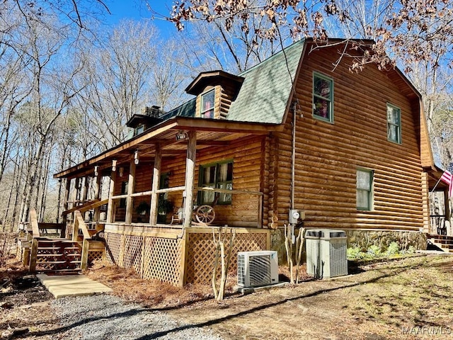 view of property exterior featuring log exterior, central AC unit, a porch, and a gambrel roof