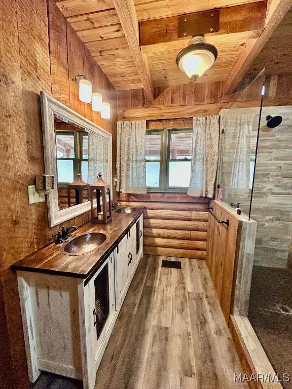 interior space with rustic walls, wood ceiling, wood finished floors, a sink, and beam ceiling