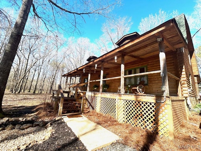 view of property exterior with covered porch and log siding