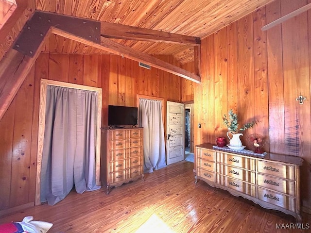 interior space featuring visible vents, lofted ceiling with beams, wood ceiling, wooden walls, and wood finished floors