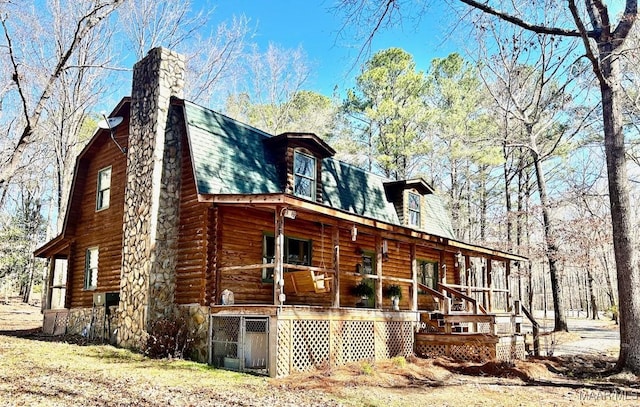 view of property exterior featuring roof with shingles, a chimney, a porch, a gambrel roof, and log siding