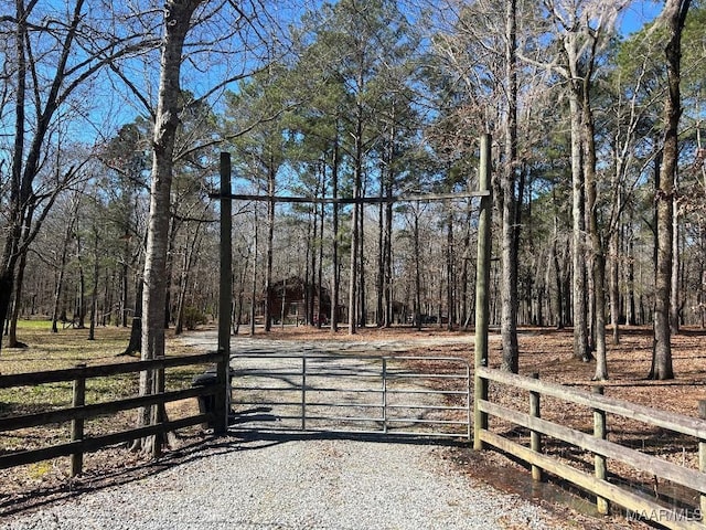 view of gate with fence and a forest view