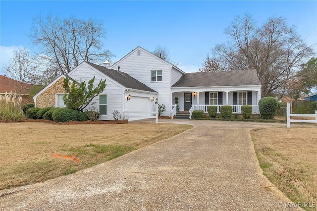 view of front of home with a porch, an attached garage, concrete driveway, stone siding, and a front yard