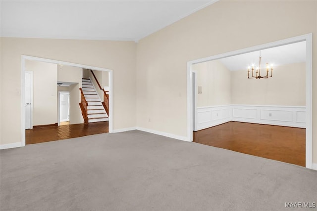 unfurnished room featuring lofted ceiling, a notable chandelier, a wainscoted wall, carpet floors, and stairs