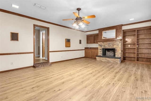 unfurnished living room featuring ornamental molding, a brick fireplace, light wood-style flooring, and baseboards