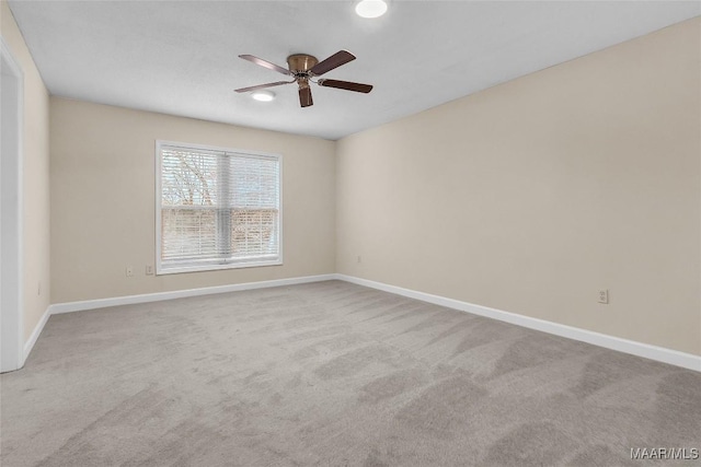 carpeted empty room featuring a ceiling fan and baseboards