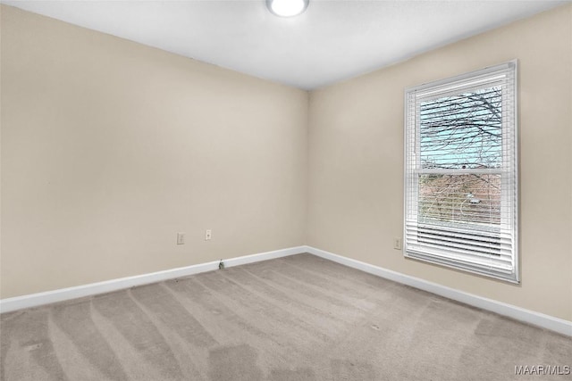 spare room with baseboards and light colored carpet