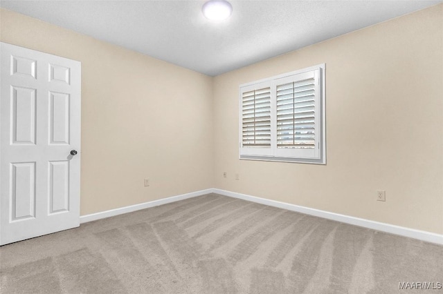 carpeted spare room featuring baseboards