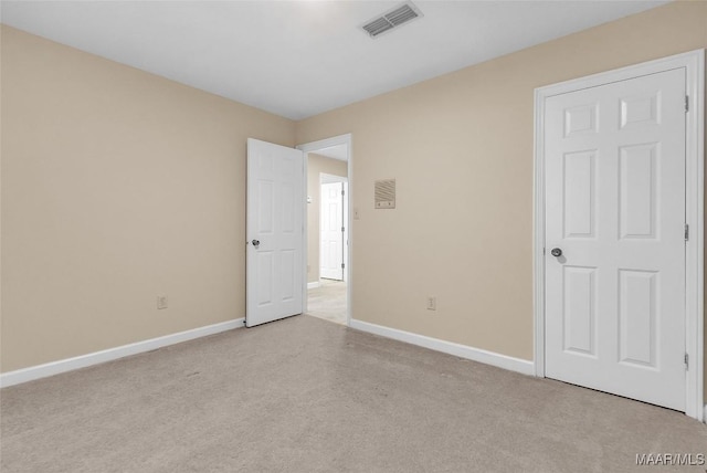 empty room with carpet, visible vents, and baseboards