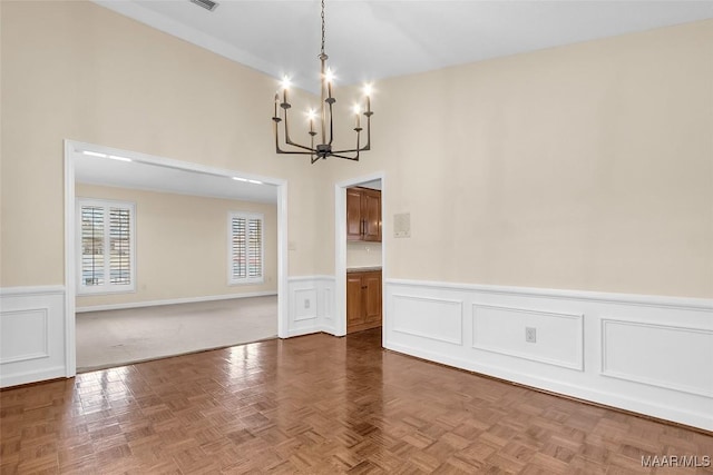 unfurnished dining area with a chandelier and wainscoting