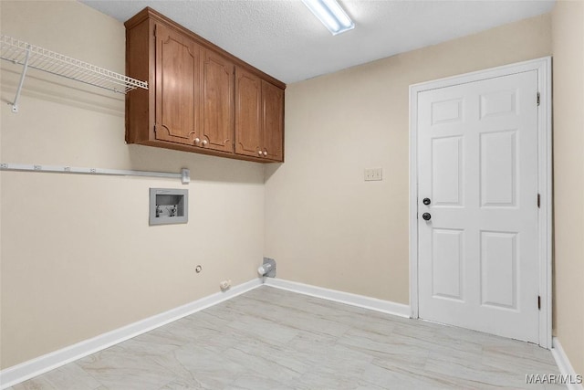 laundry area featuring hookup for a washing machine, hookup for a gas dryer, cabinet space, a textured ceiling, and baseboards