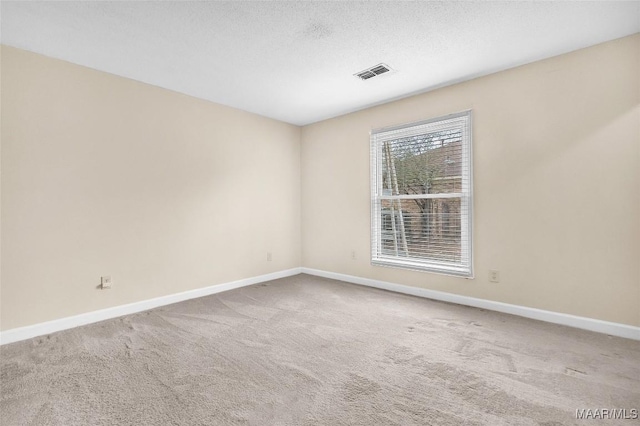 unfurnished room featuring carpet, visible vents, a textured ceiling, and baseboards