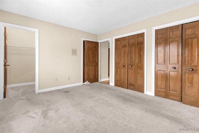 unfurnished bedroom featuring carpet floors, two closets, and baseboards