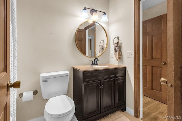 bathroom with baseboards, vanity, toilet, and wood finished floors