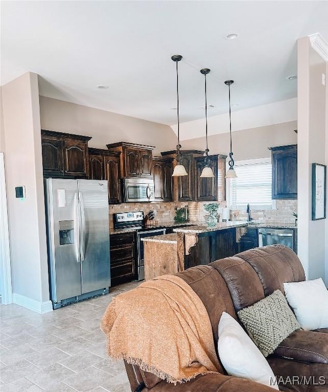 kitchen featuring decorative backsplash, appliances with stainless steel finishes, open floor plan, and dark brown cabinets