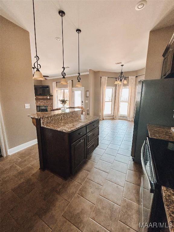 kitchen with baseboards, range, a kitchen island, light stone countertops, and pendant lighting