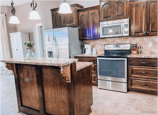 kitchen featuring appliances with stainless steel finishes, a breakfast bar, light stone counters, and decorative backsplash