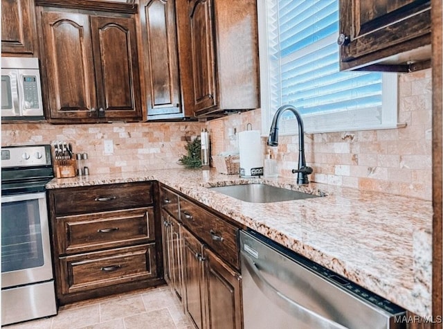 kitchen featuring stainless steel appliances, a sink, dark brown cabinetry, and tasteful backsplash