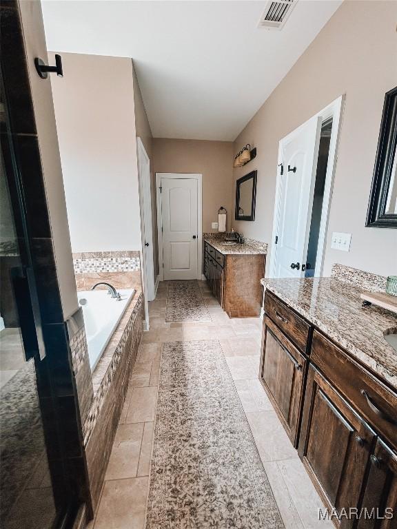 bathroom with a bath, visible vents, and two vanities