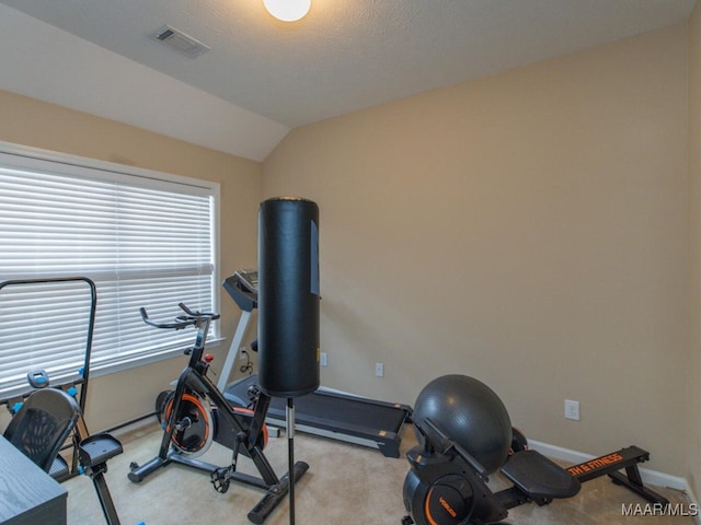 workout area with baseboards, visible vents, vaulted ceiling, and light colored carpet