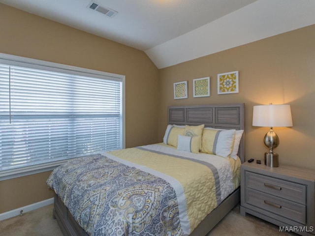 carpeted bedroom featuring lofted ceiling, baseboards, and visible vents