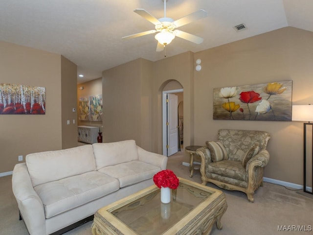 carpeted living area with arched walkways, lofted ceiling, visible vents, and baseboards