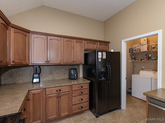 kitchen featuring lofted ceiling, washer and clothes dryer, black fridge with ice dispenser, and brown cabinets