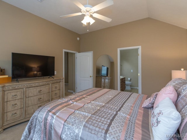 bedroom featuring a ceiling fan, lofted ceiling, light carpet, and ensuite bath