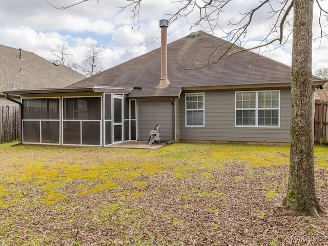 rear view of house featuring a sunroom, roof with shingles, fence, and a lawn