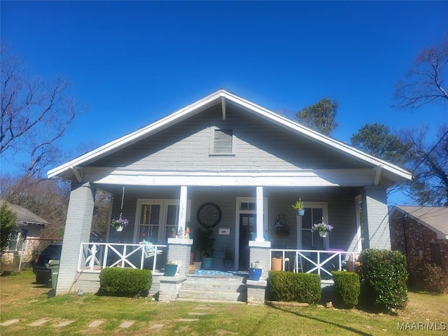 bungalow-style home featuring a porch, a front lawn, and brick siding