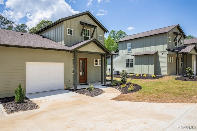 view of front facade featuring driveway, central AC unit, roof with shingles, an attached garage, and board and batten siding