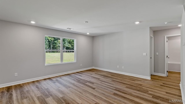 empty room featuring baseboards, visible vents, wood finished floors, and recessed lighting