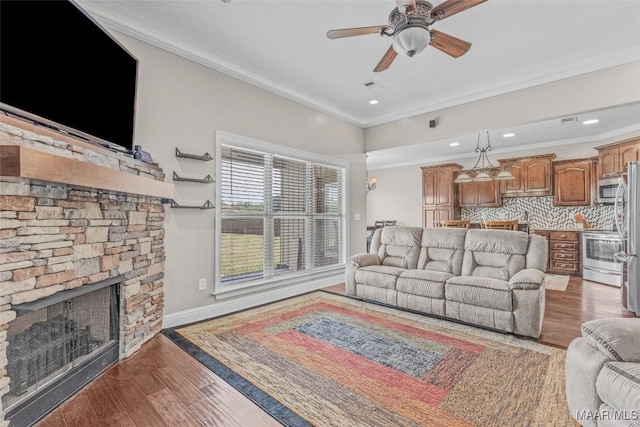 living room featuring visible vents, a fireplace, ornamental molding, and wood finished floors