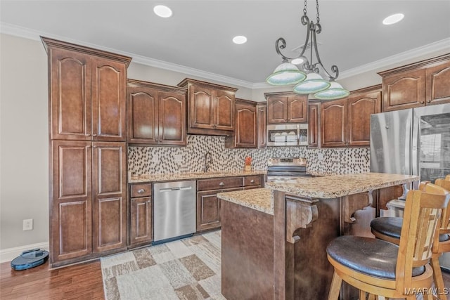 kitchen featuring tasteful backsplash, appliances with stainless steel finishes, light stone counters, a breakfast bar area, and ornamental molding