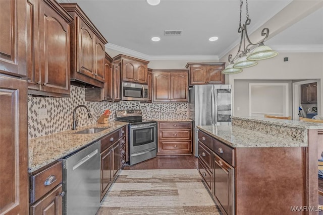 kitchen featuring a center island, visible vents, appliances with stainless steel finishes, ornamental molding, and a sink