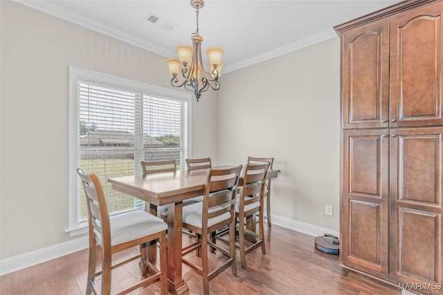 dining room with visible vents, crown molding, a notable chandelier, and wood finished floors