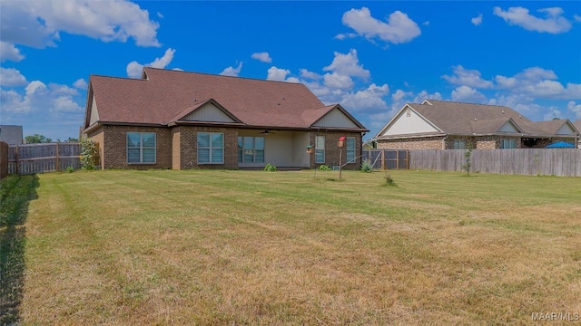 rear view of property featuring brick siding, a lawn, a fenced backyard, and a ceiling fan