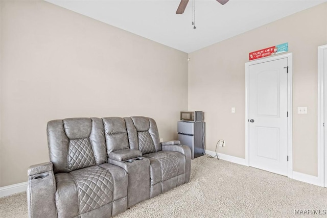 living area with light carpet, baseboards, and a ceiling fan