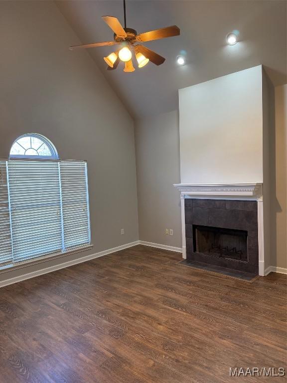 unfurnished living room with baseboards, ceiling fan, a tiled fireplace, and wood finished floors