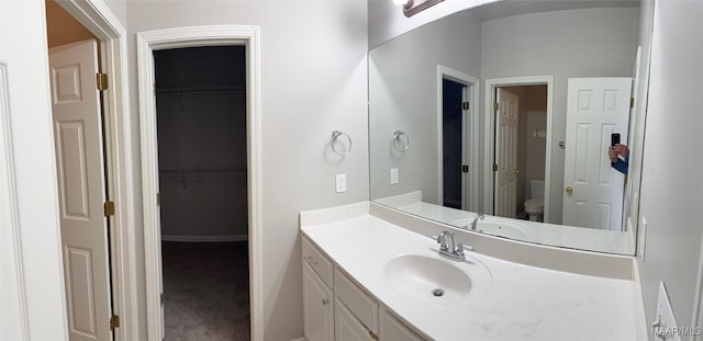 bathroom featuring vanity, toilet, and a spacious closet