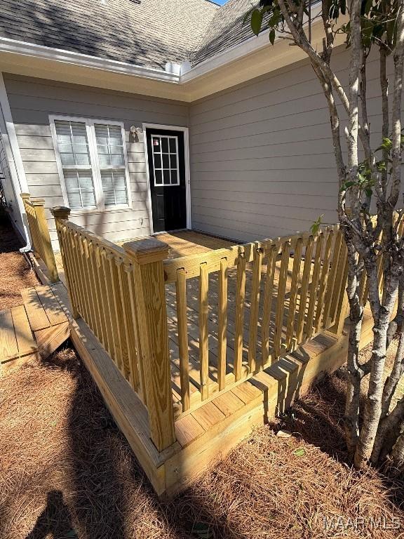 property entrance with roof with shingles and a deck