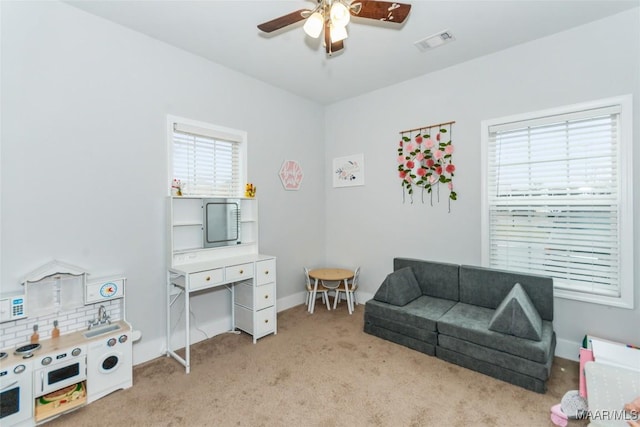living area with ceiling fan, visible vents, baseboards, and light colored carpet