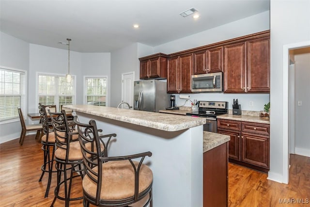 kitchen with a breakfast bar, visible vents, stainless steel appliances, and light countertops