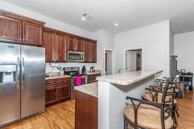 kitchen featuring appliances with stainless steel finishes, light countertops, light wood-style floors, and visible vents