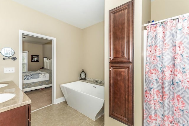 ensuite bathroom featuring tile patterned flooring, a freestanding tub, connected bathroom, a sink, and double vanity