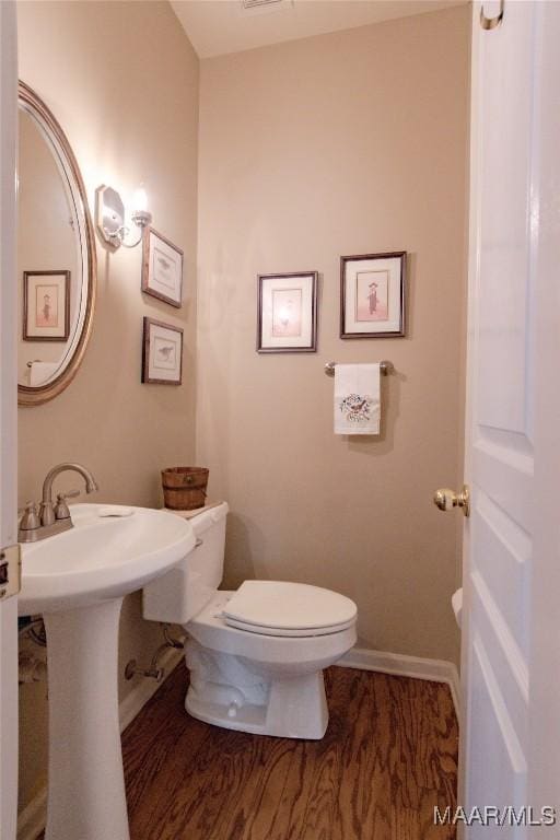 bathroom featuring baseboards, a sink, toilet, and wood finished floors