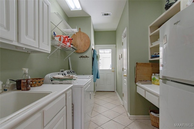 clothes washing area with cabinet space, visible vents, washing machine and dryer, a sink, and light tile patterned flooring